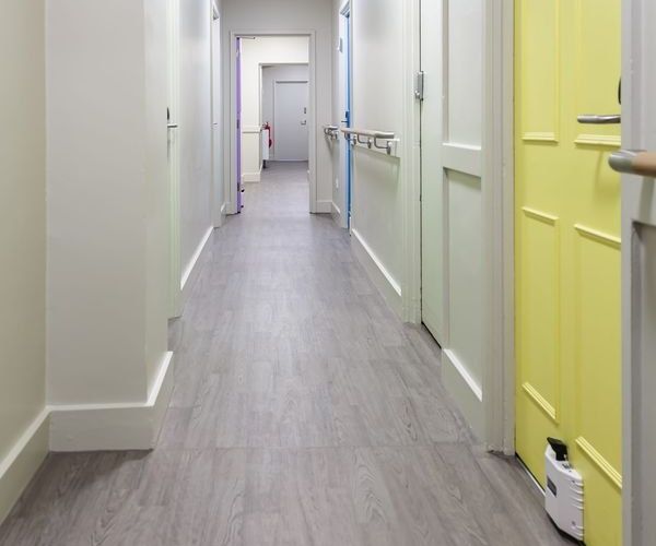 Refurbished care home corridor with new flooring, handrails and colour-coded bedroom doors